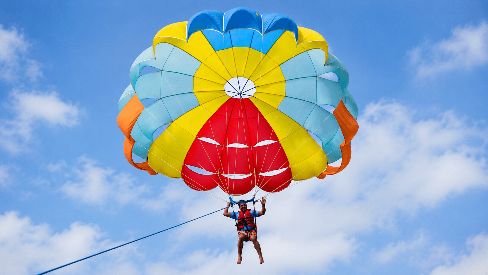 Dr. Vijay Kumar parasailing above the ocean, embracing courage and personal growth beyond his comfort zone