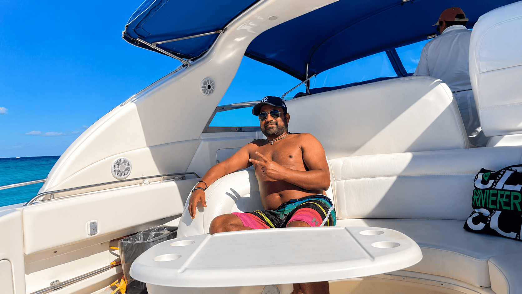 Dr. Vijay Kumar relaxing aboard a boat on the turquoise Caribbean Sea near Cancun, Mexico, under a bright blue sky, reflecting on travel, wellness, and renewed purpose
