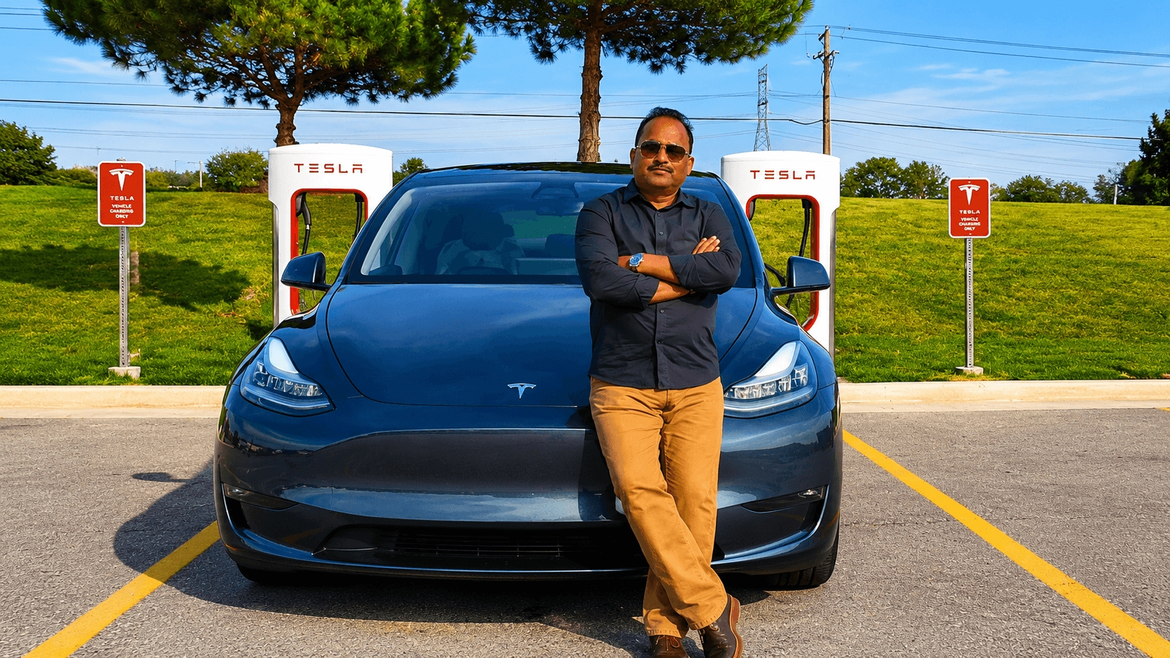 Dr. Vijay Kumar standing beside an electric vehicle at a Tesla Supercharger, symbolizing innovation, sustainable transportation, digital transformation, and the future of technology.