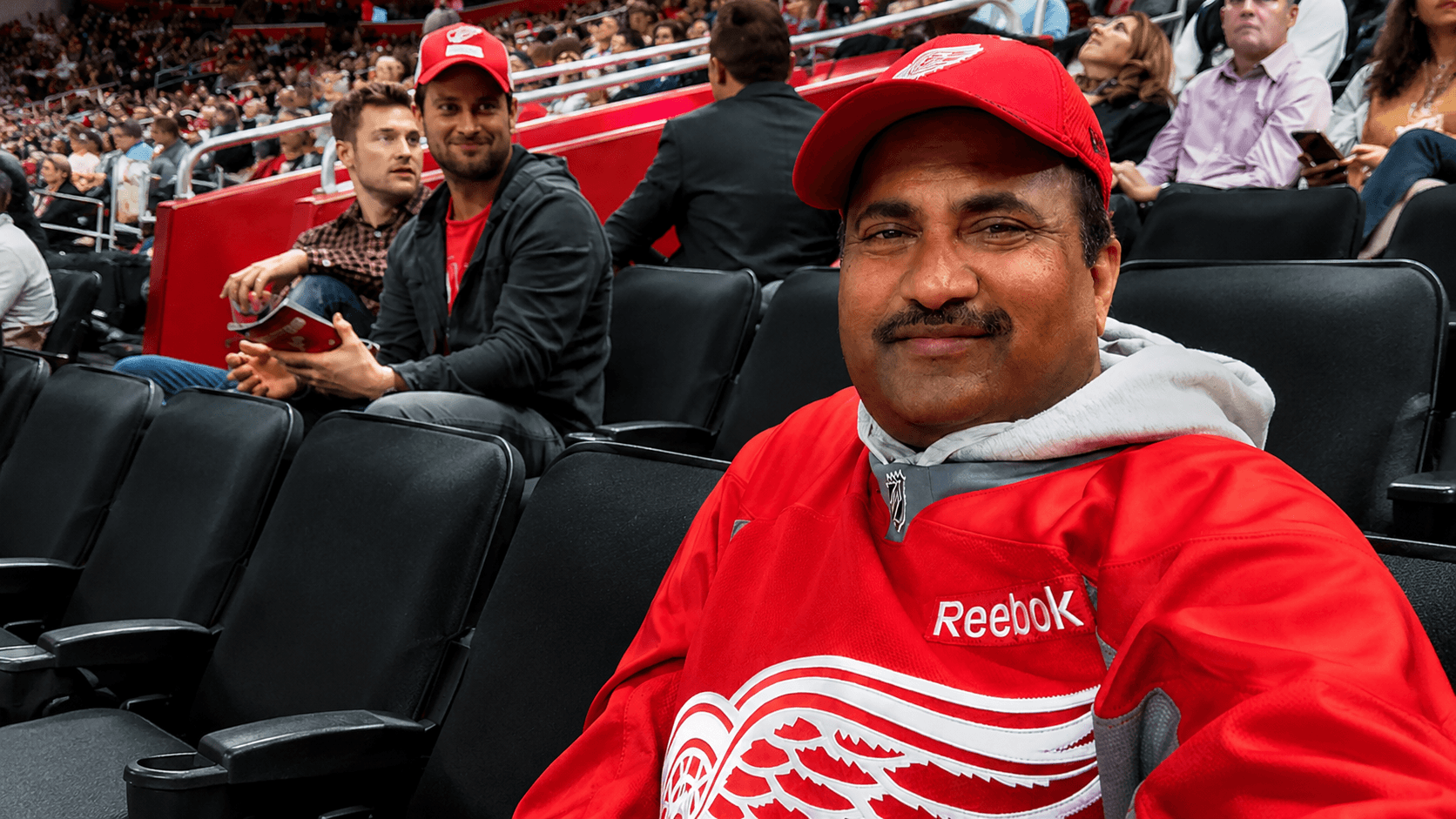 Dr. Vijay Kumar attending a Detroit Red Wings hockey game, surrounded by fans and reflecting on teamwork, resilience, discipline, leadership, community, and life lessons from sports.